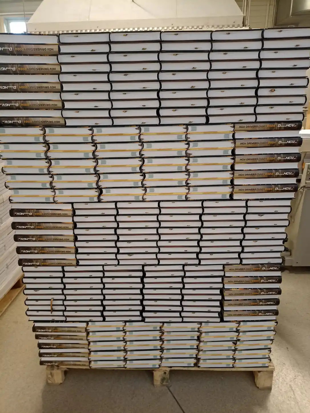 Stacks of finished HGV Drivers Diary 2024 books arranged on a pallet after binding.