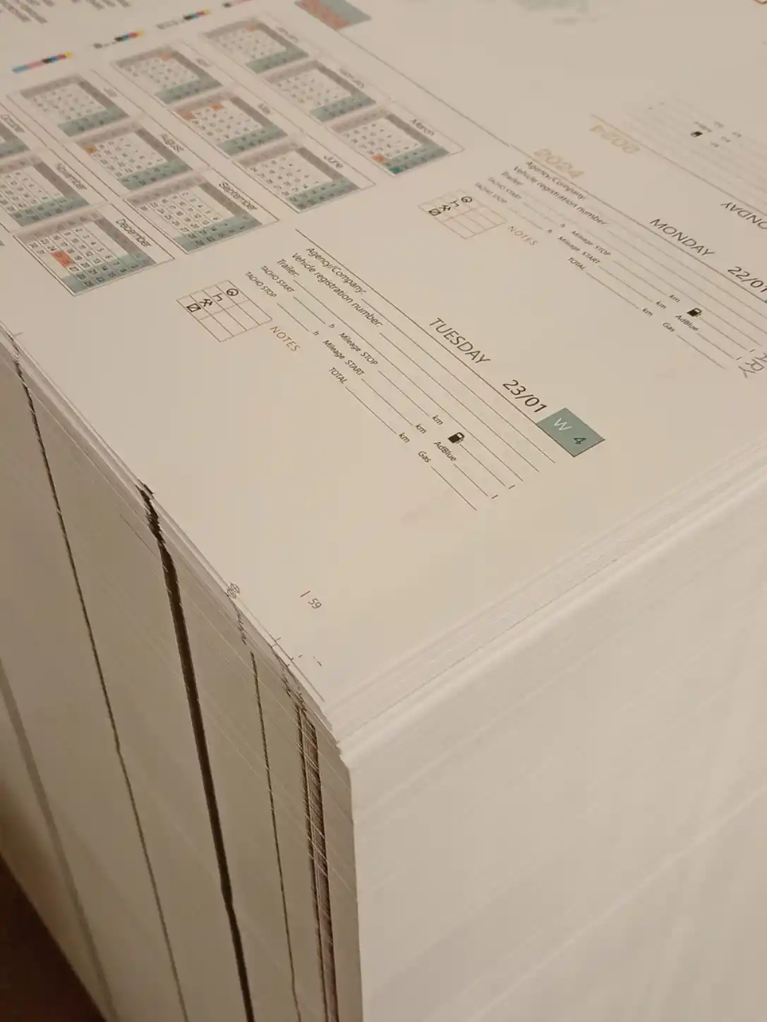 Freshly printed HGV Drivers Diary 2024 calendar pages stacked after printing.