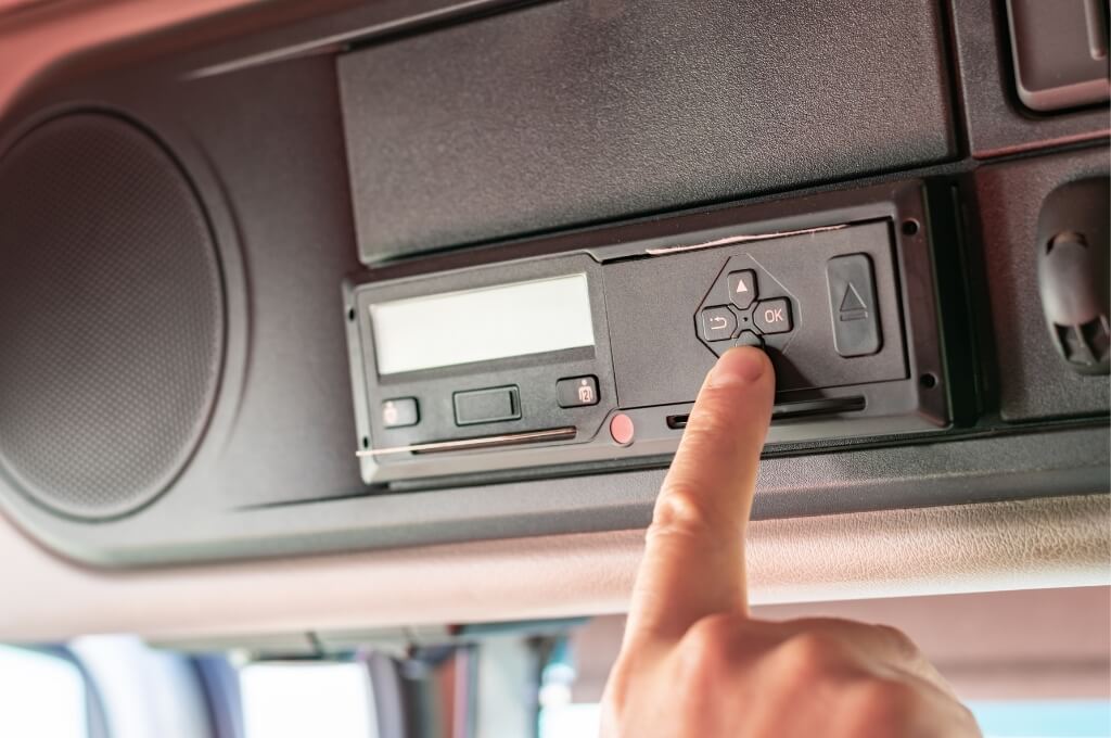 Finger operating a digital tachograph unit mounted inside a lorry cab