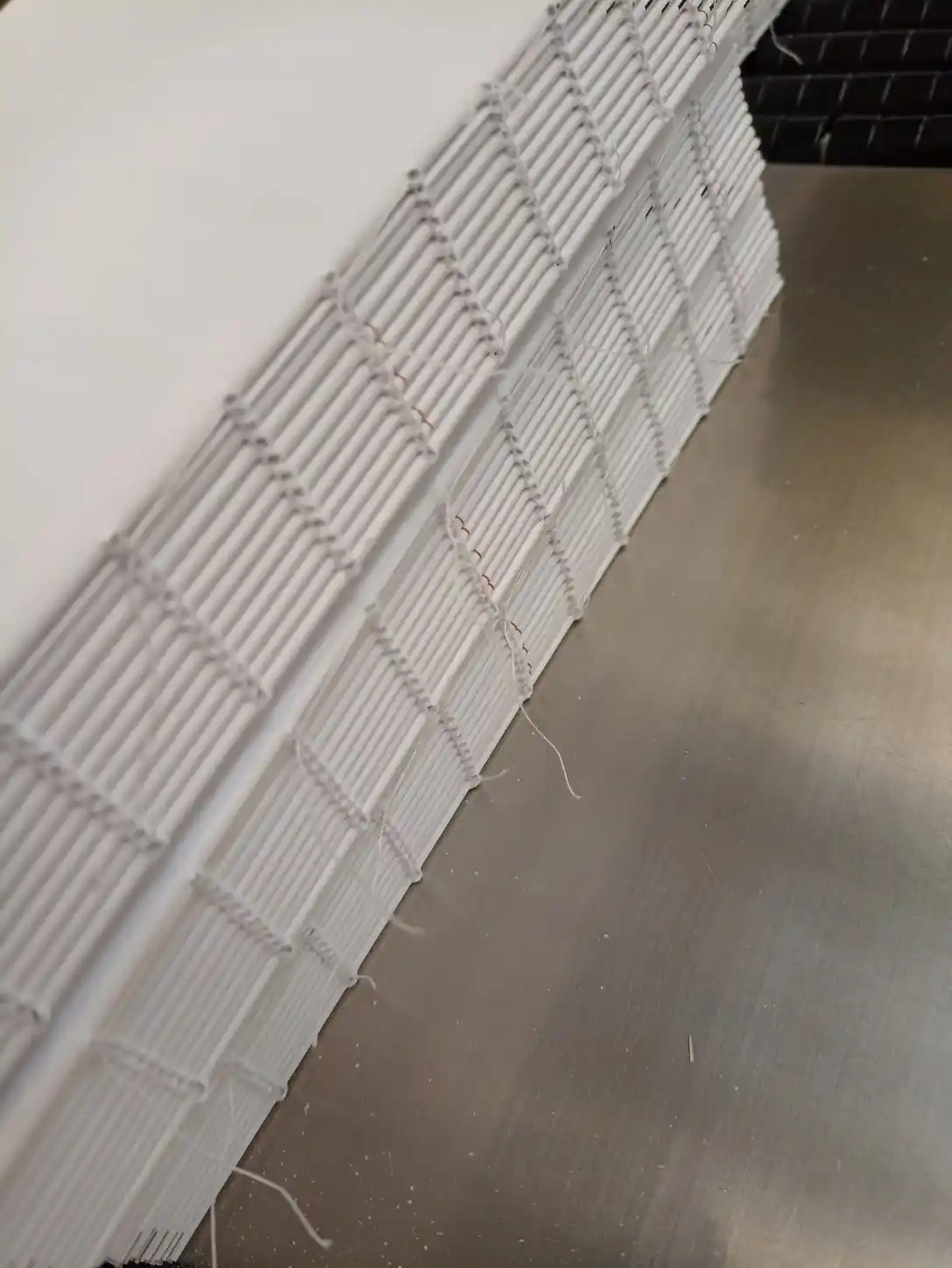Close-up of sewn HGV Drivers Diary page sections during the binding process.