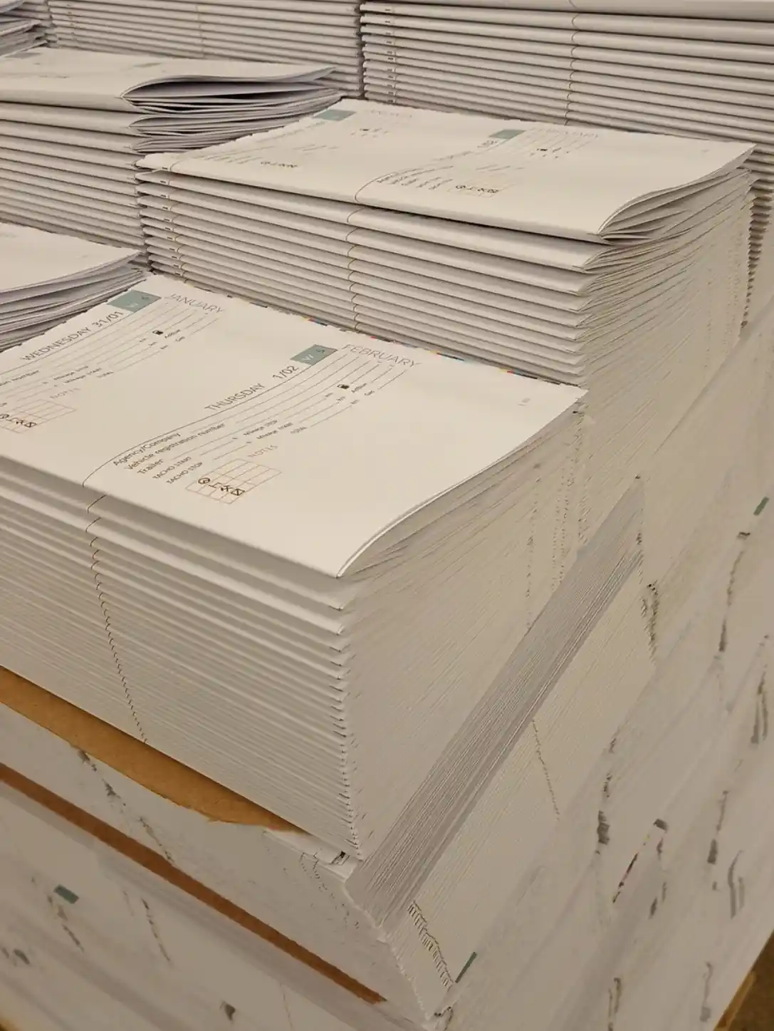 Stacks of folded HGV Drivers Diary page sections ready for the next binding stage.
