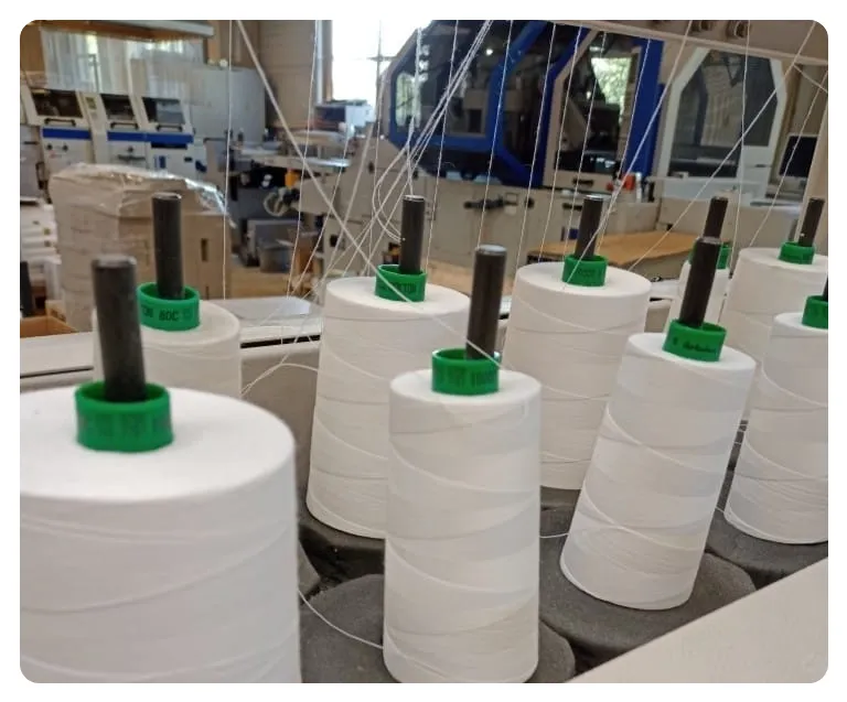 Industrial thread spools on bookbinding machine sewing HGV driver diaries in the UK